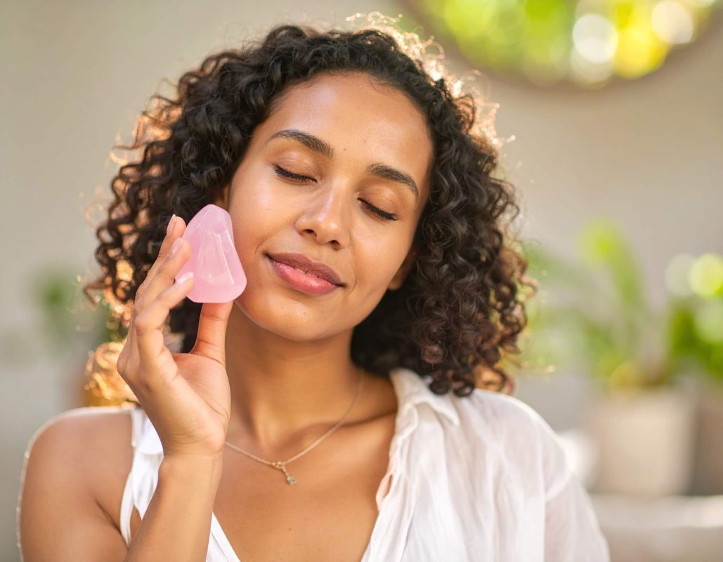 A woman holding a rose quartz stone to her cheek representing rose quartz and the heart chakra